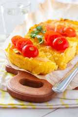 Polenta served on wood board with cherry tomatoes