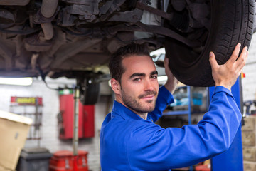 Fototapeta na wymiar Young attractive mechanic working on a car at the garage