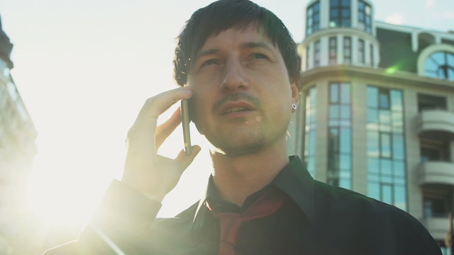 serious man in shirt and tie talking on the phone in the street 