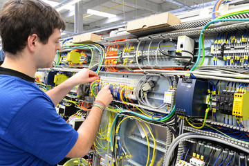 Elektroniker im Maschinenbau montiert Schaltschrank in einer Fabrik // workers mounted electronics...
