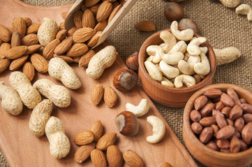 Almonds, cashew and hazelnuts in wooden bowls on wooden and burlap
