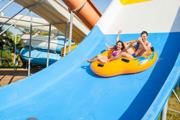 Couple sliding down a water slide