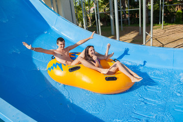 Couple sliding down a water slide