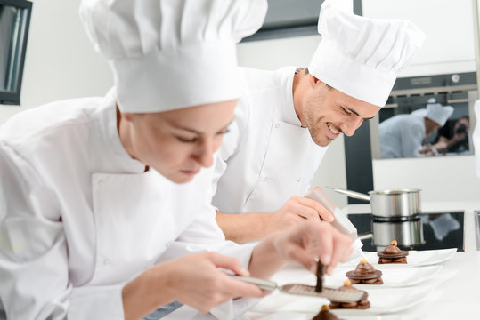 Pastry Cook Professional Team Man And Woman In Restaurant Kitchen Preparing A Chocolate Dessert