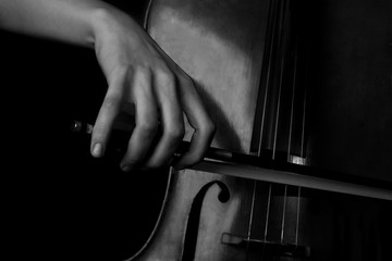 Hand of a woman playing the cello in black and white 
