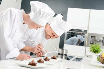 student and teacher in a professional cook school kitchen preparing a chocolate dessert