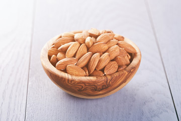 roasted almonds in wood bowl on blue wooden table