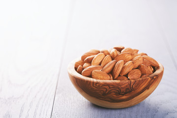 roasted almonds in wood bowl on blue wooden table