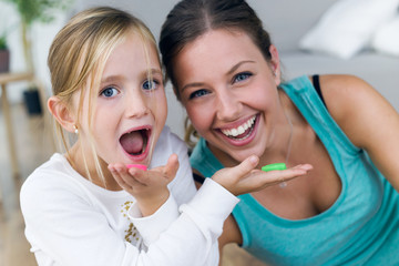 Young mother and daughter eating sweets at home.