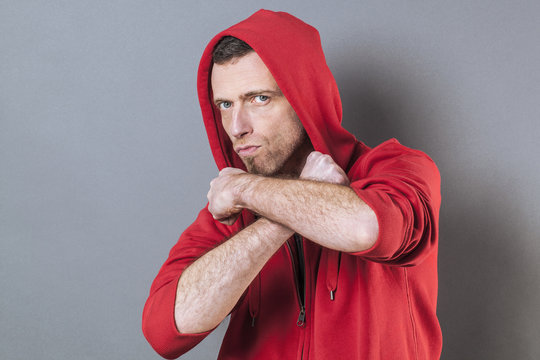 male power concept - unhappy 40s man wearing an adolescent hoodie countering fight with both arms crossed,studio shot