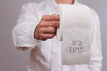 Man holding toilet paper with words it is time written on it