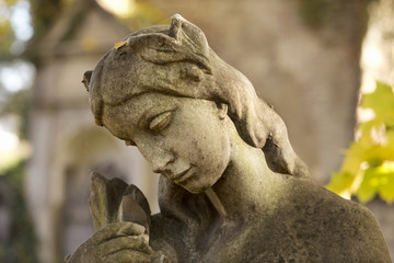 Fototapeta na wymiar Stone Girl on Tomb from autumn mystery old Prague Cemetery, Czech Republic