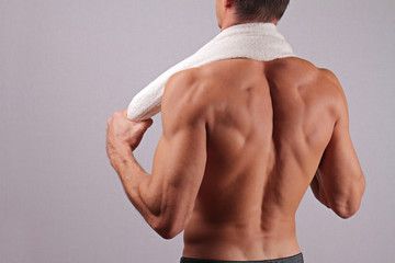 Back view of strong muscular male body, closeup of fitness man with a white towel slung around his neck. bodybuilding, work out, sport, hard work, motivation, active lifestyle concept - Powered by Adobe