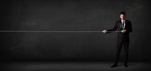 Obraz premium Businessman pulling rope on grey background