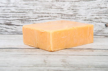 A block of cheddar cheese over wooden background