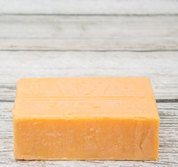 A block of cheddar cheese over wooden background