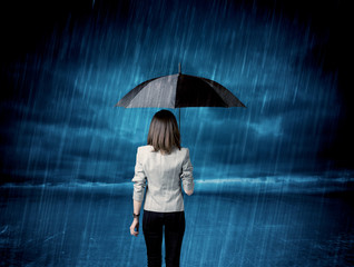 Business woman standing in rain with an umbrella