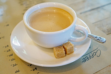 Cup of coffee with cane sugar and smiley spoon.