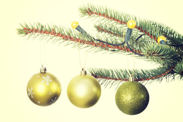 Three christmas balls hanging on a twig.