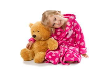 Little girl in warm pink bathrobe with Teddy bear  on a white ba
