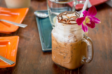 Iced coffee with milk in vintage jar and orchid flower decoratio