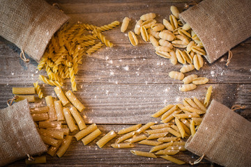 uncooked Italian pasta spilling on to a wood table