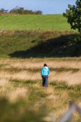 Woman walking on the meadow against a hill