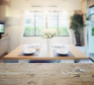 wooden table top with blur of modern dining room interior.