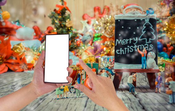 image of male hand using phone and Christmas ornaments