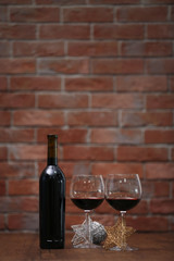 Red wine and Christmas ornaments on wooden table on wall brick background