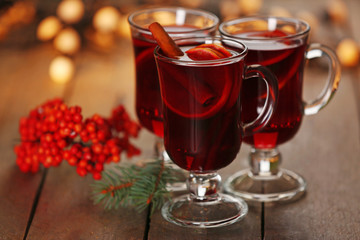 Mulled wine with spices and Christmas tree on wooden background
