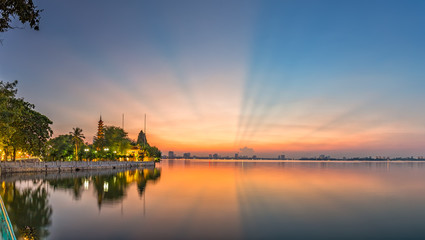 Naklejka premium Sunray side West Lake, Hanoi, Vietnam with pink ray rays sky illuminated side Tran Quoc pagoda makes the sunset as a theatrical dance in the sky