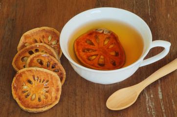 cup of bael juice with wooden spoon on wooden background