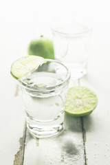 Vodka shot with lime and salt on wooden table background