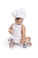 Funny adorable baby boy chef sitting and playing with kitchen equipment