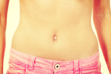 Naklejka premium Slim woman wearing jeans showing belly.
