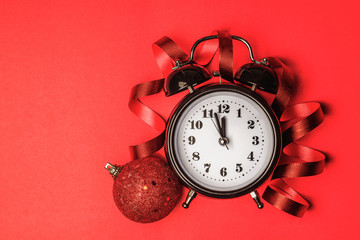 Overhead view of a clock and christmas decoration on red paper b