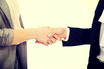 Two women in office outfits giving handshake.
