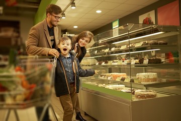 Family near display with cakes in a grocery store