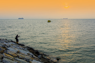 Fototapeta premium silhouette of a fisherman with boat passing by during sunset
