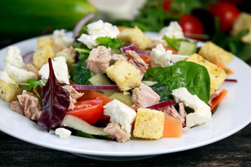 Tuna salad with Spinach, rocket, red ruby chard, tomatoes, cucumbers, carrot, red onion, white chesse, croutons on old wooden table