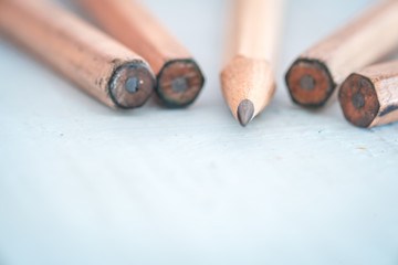 Old pencil on a light blue wooden desk. Shallow depth of field.