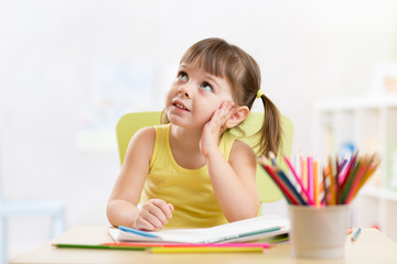 thoughful child girl drawing with colorful pencils