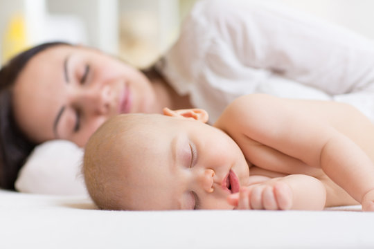 Woman and baby boy relaxing in a white bedroom. 