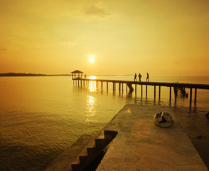 Fototapeta premium sylwetka człowieka idącego na molo podczas złotego zachodu słońca