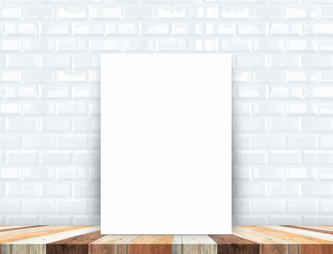 Blank white poster leaning at tropical wood table top with white
