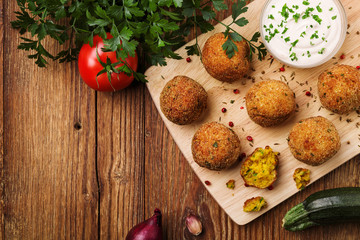 Chickpea falafel balls on a wooden desk with vegetables