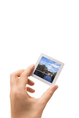 Male hand holding a framed piece of slide film isolated on white