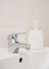 Running water out of a chrome faucet in a clean white bathroom