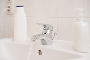 Running water out of a chrome faucet in a clean white bathroom